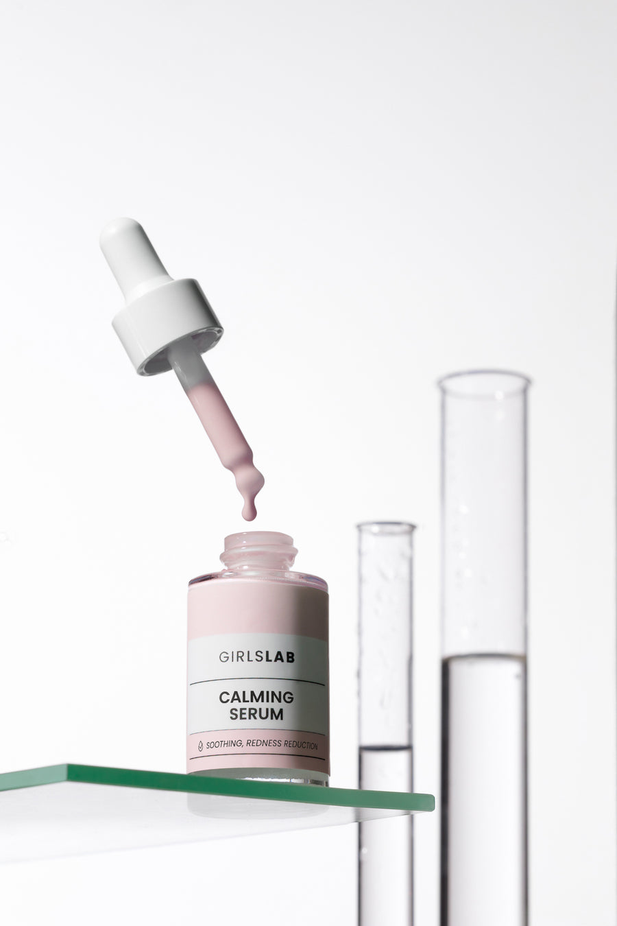 Serum łagodzące GirlsLAB z pipetą na tle laboratoryjnego szkła